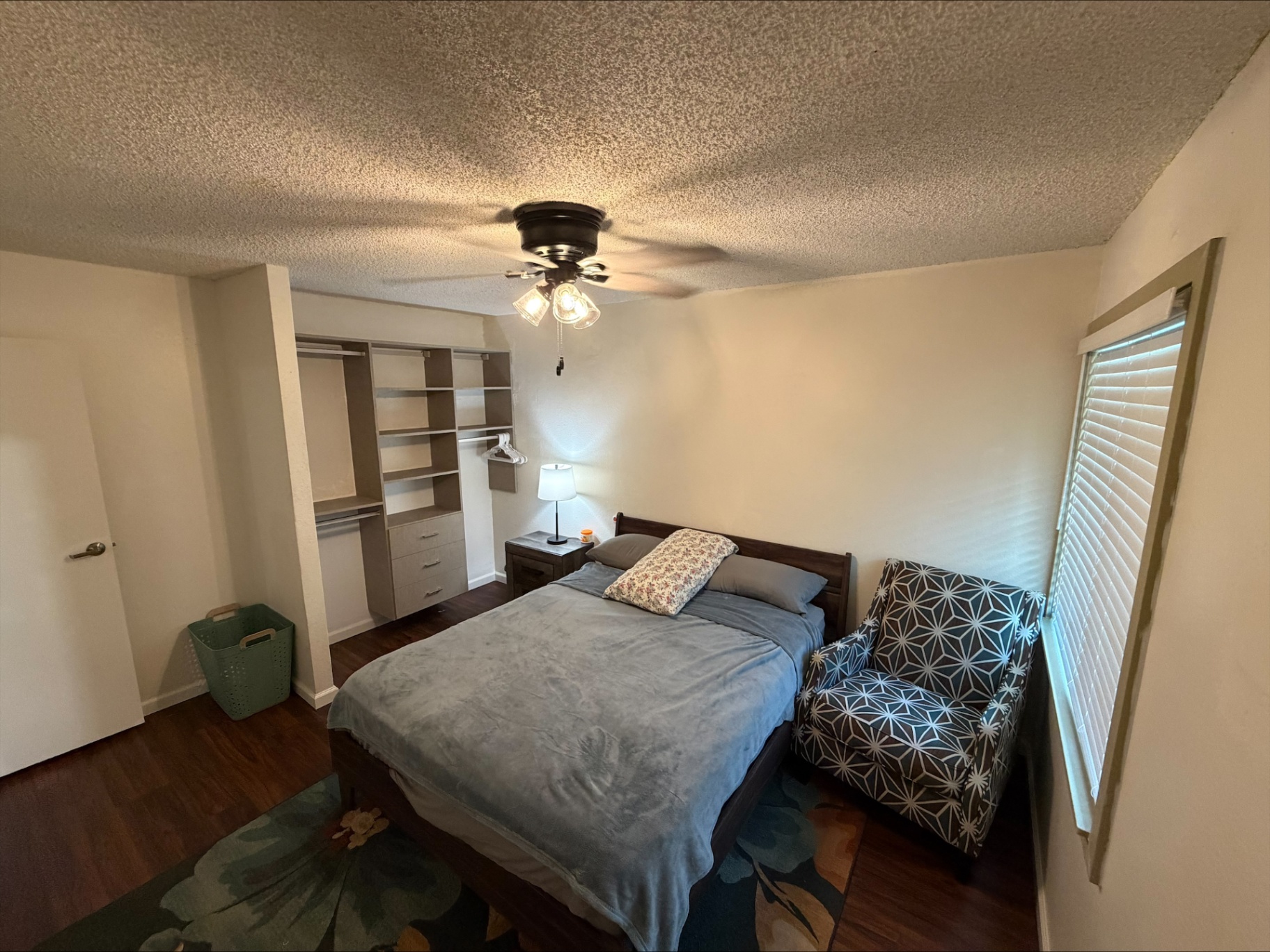 Resident bedroom with queen bed, seating chair, and closet storage