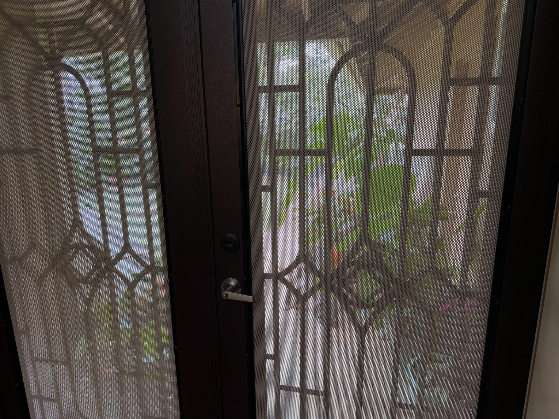 Ornate front security doors with garden view beyond