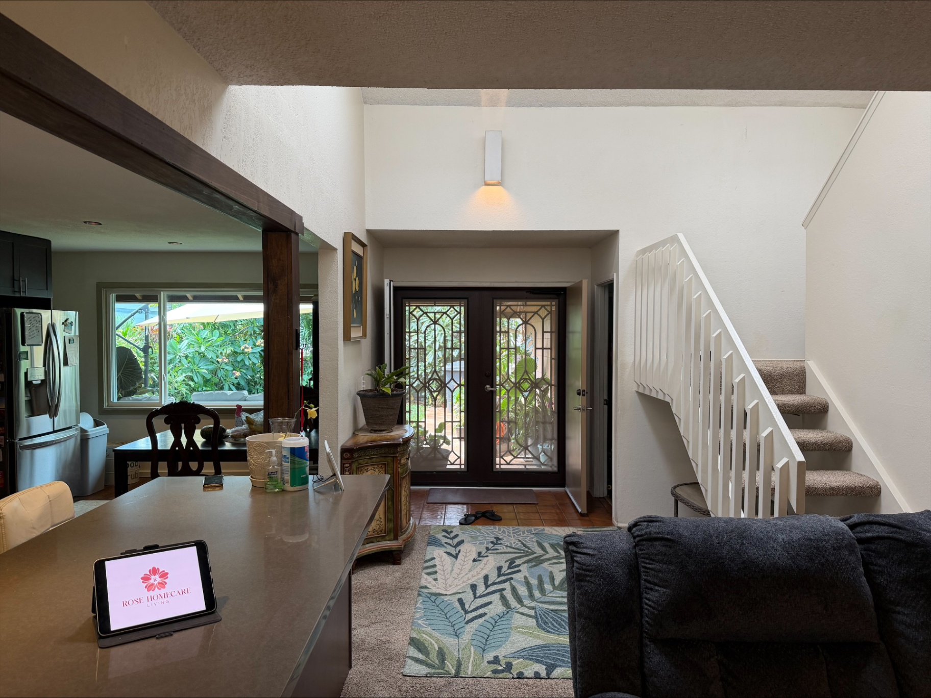 Warm entryway with staircase, decorative front doors, and garden view